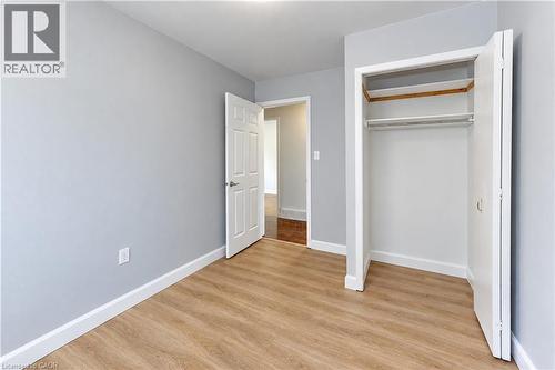 Neutral wall color, wood-finish flooring, white trim, recessed lighting, and a bi-fold door closet with shelving - 64 Stanley Street, Cambridge, ON 