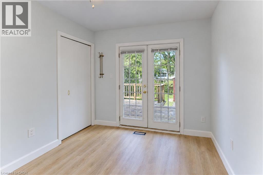 Light-toned walls, wood-finish flooring, sliding closet door, and French doors opening to an exterior wood deck - 64 Stanley Street, Cambridge, ON