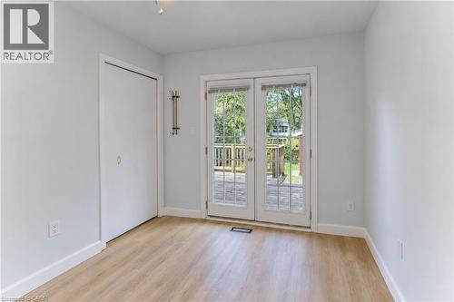 Light-toned walls, wood-finish flooring, sliding closet door, and French doors opening to an exterior wood deck - 64 Stanley Street, Cambridge, ON 