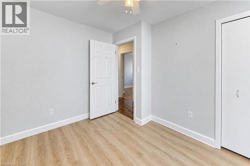 Wood-finish flooring, white panel door, white trim, and a built-in closet with white doors - 64 Stanley Street, Cambridge, ON 