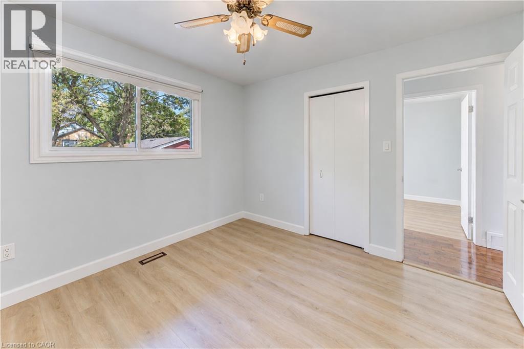 Wood-finish flooring, white trim throughout, built-in closet with bi-fold doors, and a ceiling fan with integrated lighting - 64 Stanley Street, Cambridge, ON