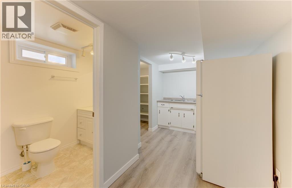 Full-size refrigerator, track lighting, wood-finish flooring, built-in shelving, and a vanity with an integrated sink - 64 Stanley Street, Cambridge, ON