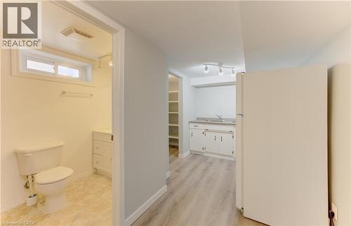 Full-size refrigerator, track lighting, wood-finish flooring, built-in shelving, and a vanity with an integrated sink - 64 Stanley Street, Cambridge, ON 