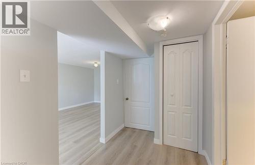Light wood-finish flooring, neutral wall paint, white trim, bi-fold closet doors, and flush-mount ceiling light fixtures - 64 Stanley Street, Cambridge, ON 