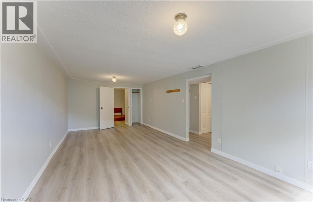 Spacious room with wood-finish flooring, two doors, and overhead lighting - 64 Stanley Street, Cambridge, ON