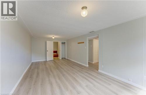 Spacious room with wood-finish flooring, two doors, and overhead lighting - 64 Stanley Street, Cambridge, ON 