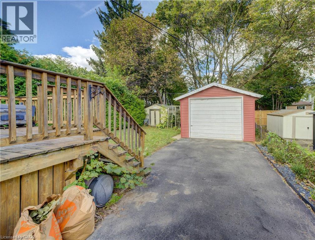 Detached garage with a paneled door, accompanied by an asphalt driveway and a wood-decked patio - 64 Stanley Street, Cambridge, ON