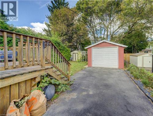 Detached garage with a paneled door, accompanied by an asphalt driveway and a wood-decked patio - 64 Stanley Street, Cambridge, ON 