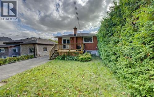 Rear exterior with brick facade, wood deck, and built-in privacy hedge - 64 Stanley Street, Cambridge, ON 