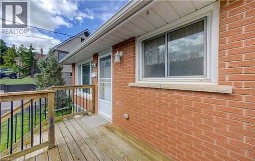 Brick exterior with a wood deck, white window trim, and exterior wall lighting - 64 Stanley Street, Cambridge, ON 