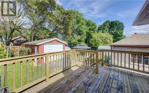 Expansive outdoor deck with wood railing, detached garage with red siding, and a paved driveway - 64 Stanley Street, Cambridge, ON 