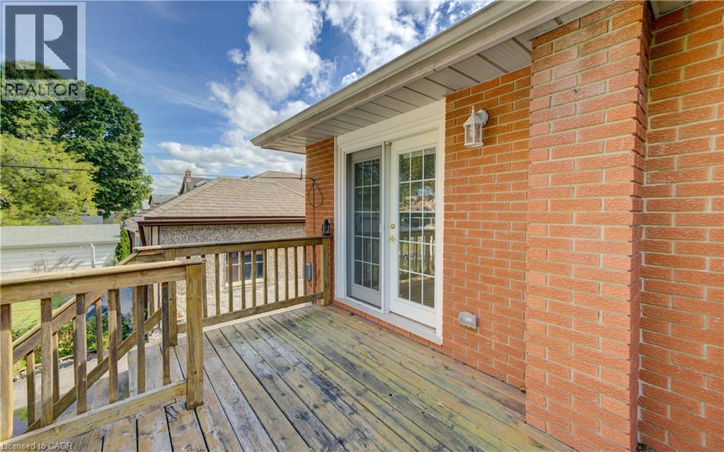Exterior brick wall with an attached deck featuring wood railing and wood-finish flooring - 64 Stanley Street, Cambridge, ON
