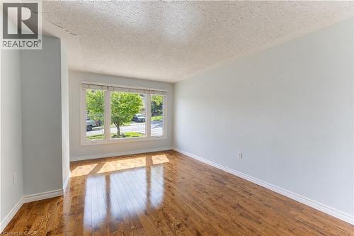 Wood-finish flooring with a high-gloss finish, large window with multiple panes, white trim, and light-toned walls - 64 Stanley Street, Cambridge, ON 