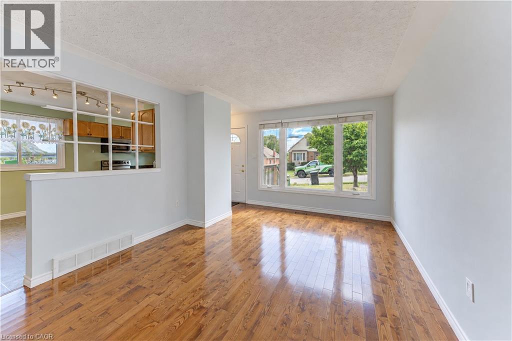 Hardwood flooring, large front-facing window, interior half-wall with grid detailing, recessed lighting, and kitchen cabinetry - 64 Stanley Street, Cambridge, ON