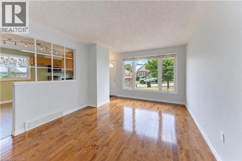 Hardwood flooring, large front-facing window, interior half-wall with grid detailing, recessed lighting, and kitchen cabinetry - 64 Stanley Street, Cambridge, ON 