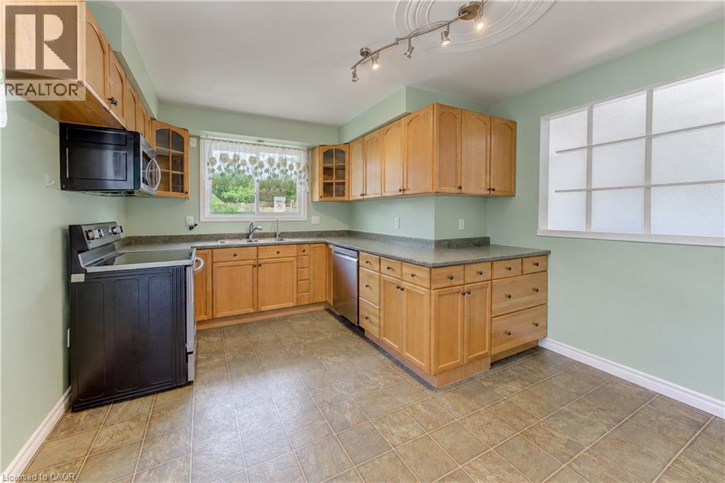 Kitchen featuring wood cabinetry, stone-finish countertops, and tile flooring - 64 Stanley Street, Cambridge, ON