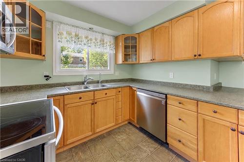 U-shaped kitchen layout featuring wood cabinetry, a double basin stainless steel sink, a stainless steel dishwasher, and tile flooring - 64 Stanley Street, Cambridge, ON 