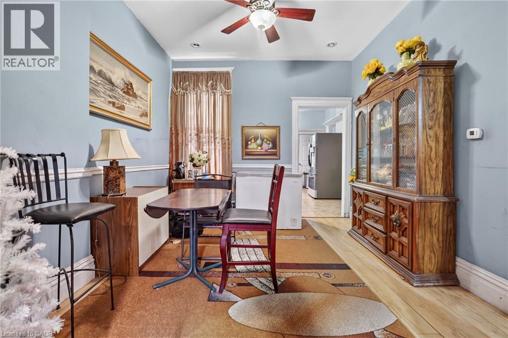Pale blue walls with white crown molding, wood-finish flooring, and a ceiling fan with light fixture - 199 N Locke Street N, Hamilton, ON
