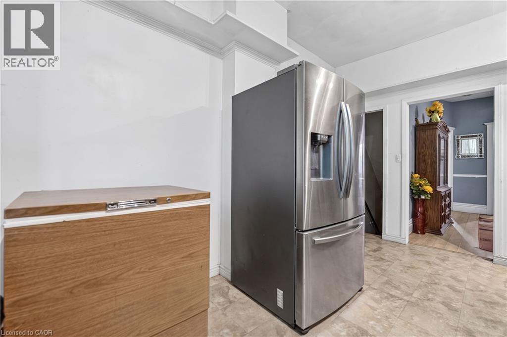 Stainless steel refrigerator with a water and ice dispenser, white crown molding, and neutral-toned floor tile - 199 N Locke Street N, Hamilton, ON