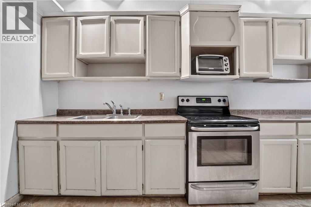 White cabinetry, stainless steel range, double basin sink, and wood-finish flooring - 199 N Locke Street N, Hamilton, ON