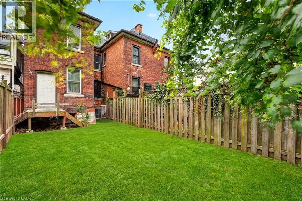 Expansive grassy yard area with wood fencing and brick exterior - 199 N Locke Street N, Hamilton, ON