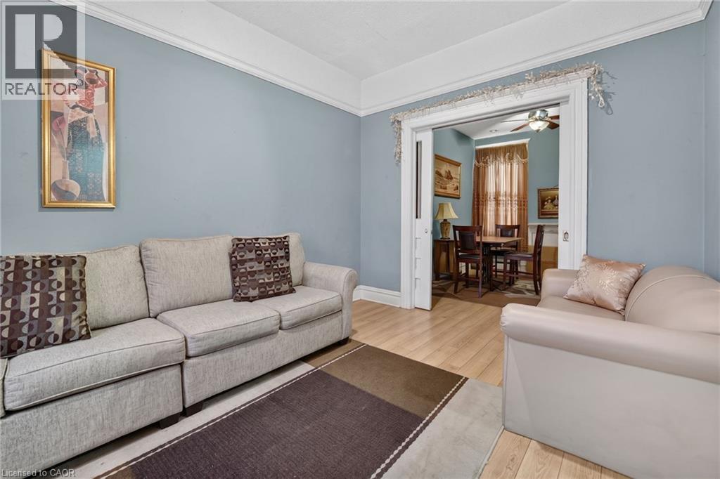 Light-toned wood-finish flooring, crown molding, and a wide cased opening with pocket doors - 199 N Locke Street N, Hamilton, ON