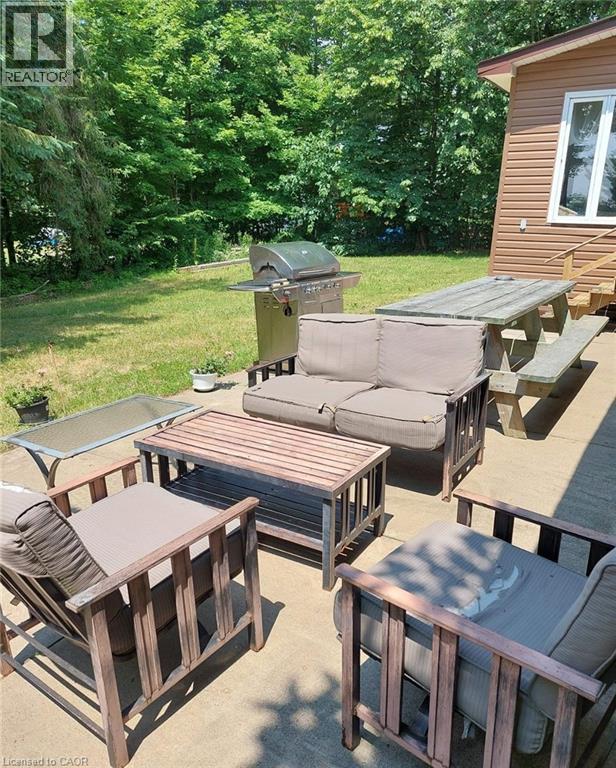 Concrete patio area featuring a built-in picnic table, and exterior stairs leading to the building - 16431 Highway 35, Algonquin Highlands, ON