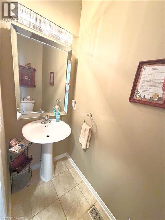 Pedestal sink with chrome faucet, framed mirror, and tile flooring - 40 Stornoway Crescent, Huron East, ON