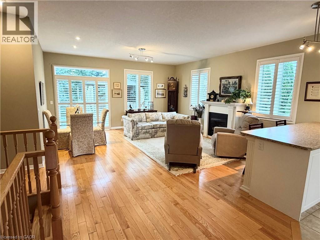 Hardwood flooring throughout, fireplace with mantel, white window shutters, recessed ceiling lighting, and a breakfast bar with stone-look countertop - 40 Stornoway Crescent, Huron East, ON