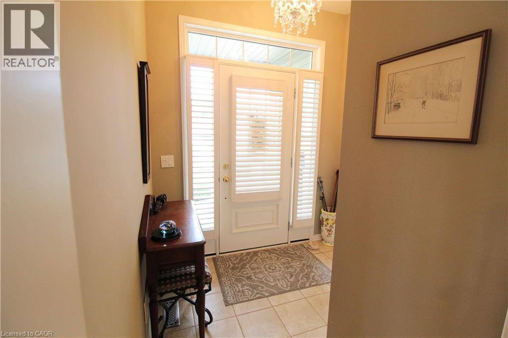 Entryway featuring a white paneled door with louvered sidelights and transom window, overhead chandelier, and tile flooring - 40 Stornoway Crescent, Huron East, ON