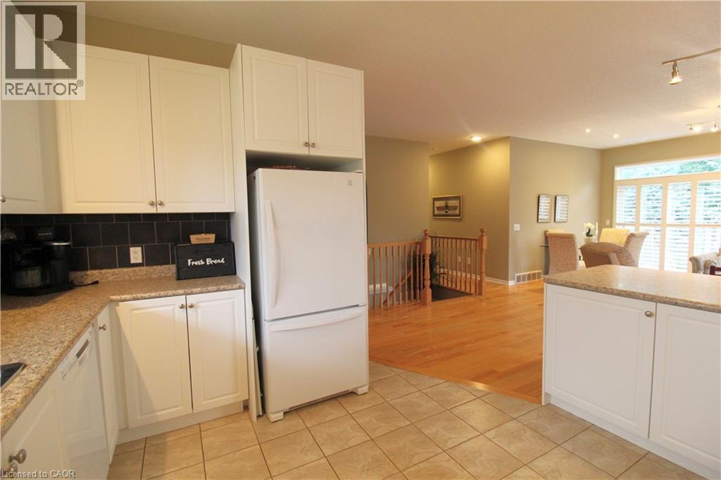 Kitchen featuring white cabinetry, a dark tile backsplash, and light-colored countertops - 40 Stornoway Crescent, Huron East, ON