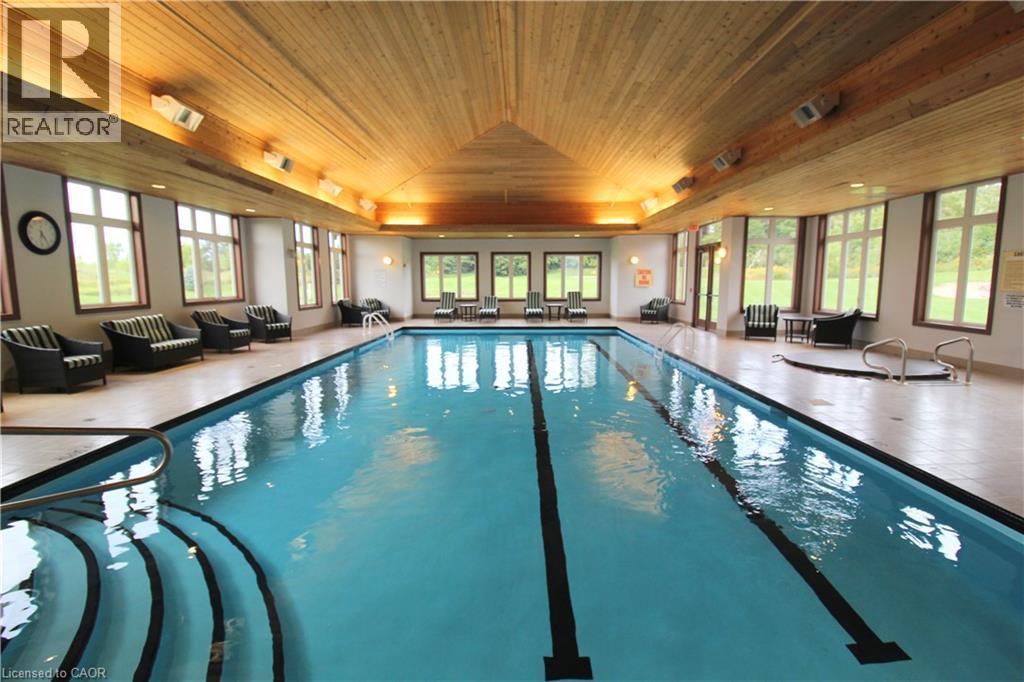 Indoor swimming pool with integrated spa and wood-paneled vaulted ceiling - 40 Stornoway Crescent, Huron East, ON