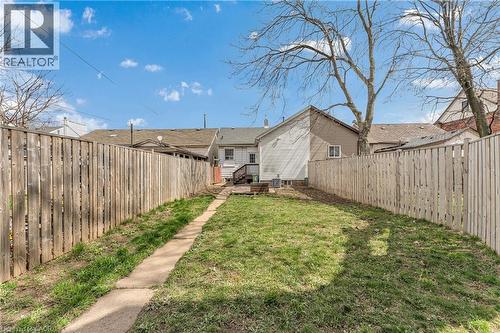Fenced backyard with a concrete pathway and mature trees - 101 Emerald Street N, Hamilton, ON 