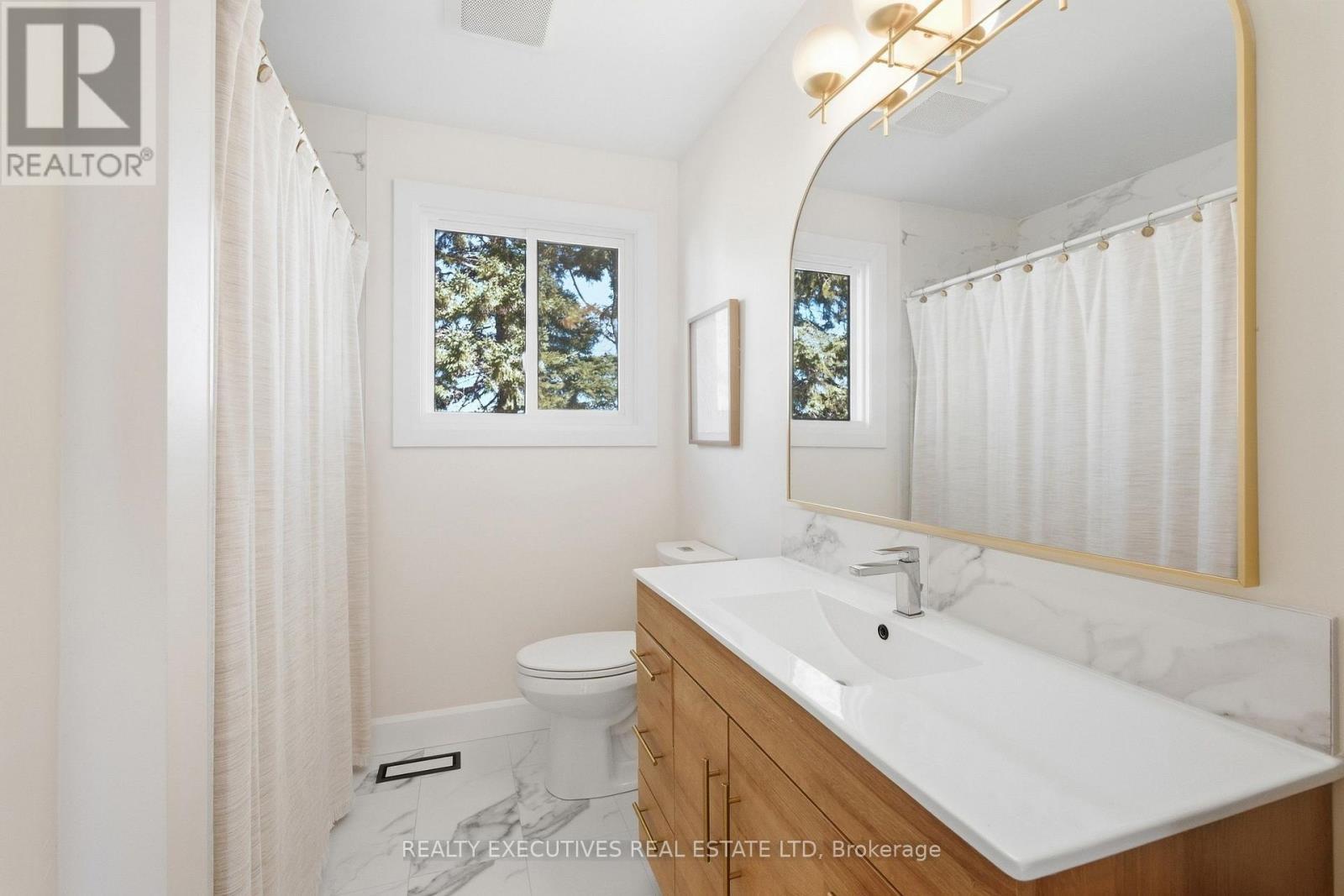 Modern vanity with gold mirror and light fixture - 11895 Cloverdale Road, North Dundas, ON