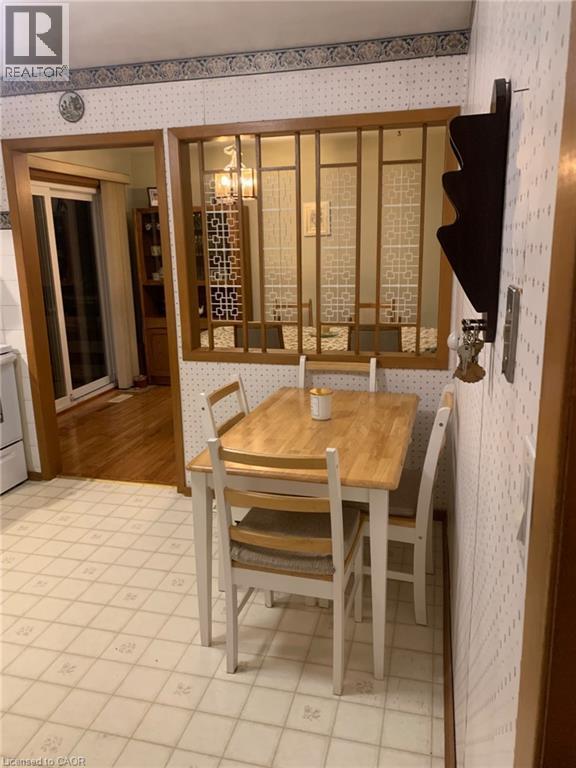 Wood-finish room divider with decorative panels, light-toned patterned wall covering, tile flooring, and a sliding glass door - 410 Lakeview Drive, Waterloo, ON