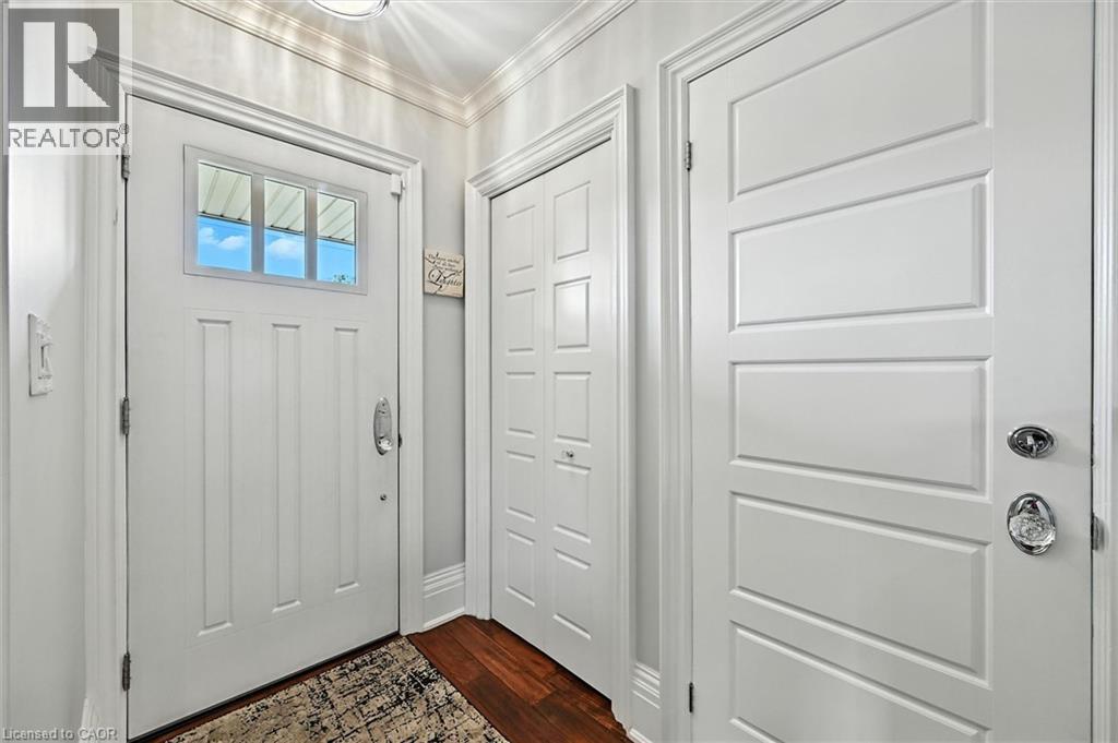 Entryway featuring a white paneled door with transom windows, polished chrome hardware, and wood-finish flooring - 2209 Ghent Avenue, Burlington, ON