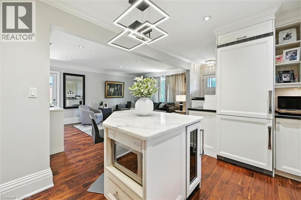 Hardwood flooring, kitchen island with a light-toned countertop, built-in panel-front refrigerator, built-in microwave, and recessed lighting - 2209 Ghent Avenue, Burlington, ON