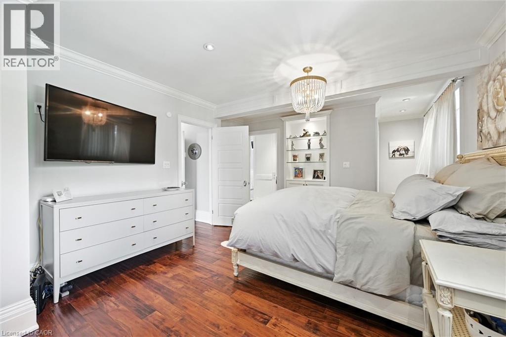 Rich wood-finish flooring, recessed lighting, crown molding, and a built-in display cabinet with glass shelving - 2209 Ghent Avenue, Burlington, ON