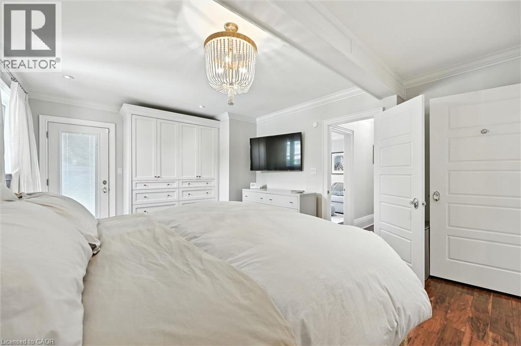 Decorative chandelier, white built-in cabinetry, wood-finish flooring, white paneled doors, and ceiling beam - 2209 Ghent Avenue, Burlington, ON