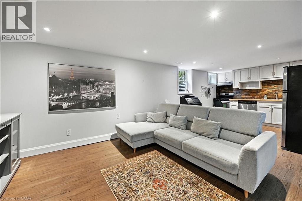 Recessed lighting, wood-finish flooring, white cabinetry, dark stone backsplash, and stainless steel dishwasher - 2209 Ghent Avenue, Burlington, ON
