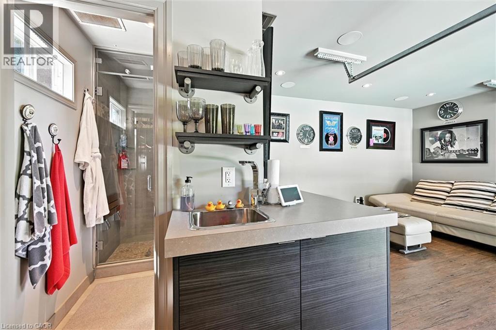 Wet bar with a single basin sink, floating shelving, and dark wood-finish cabinetry - 2209 Ghent Avenue, Burlington, ON