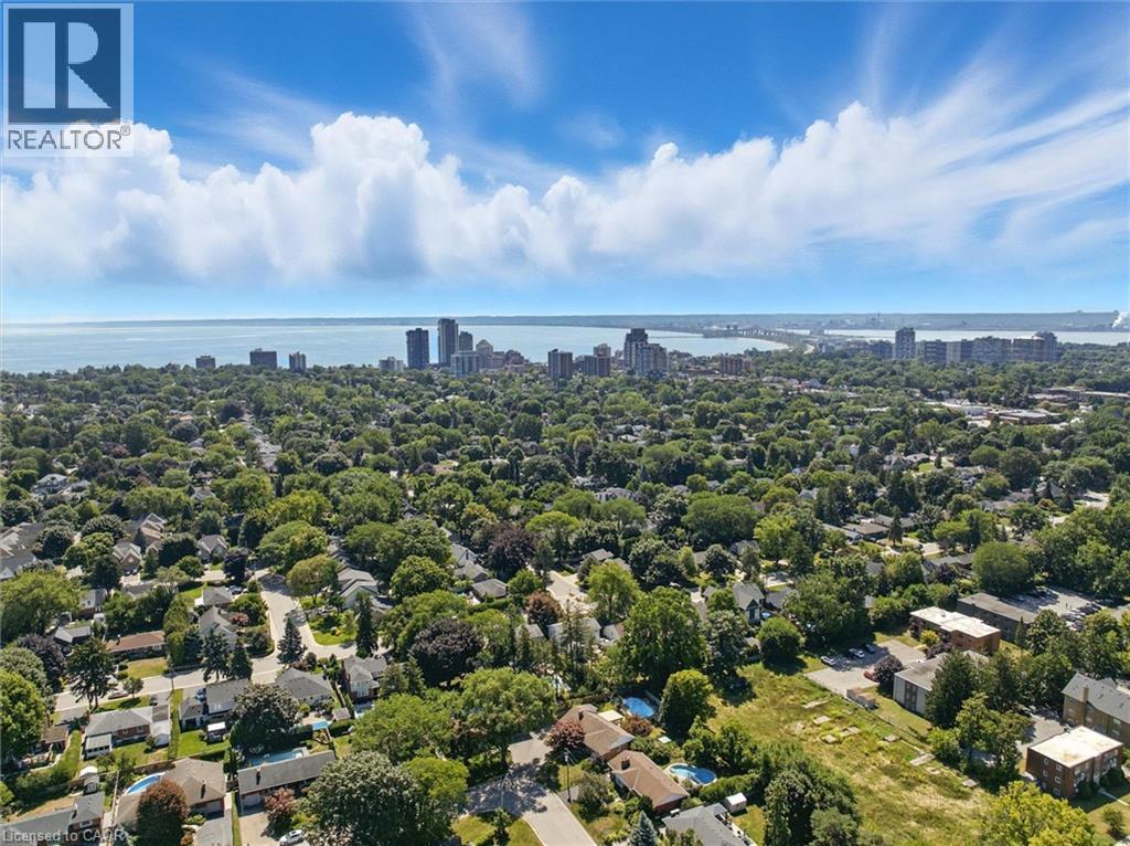 Expansive area featuring mature tree canopies, residential structures, and a distant cityscape along the water - 2209 Ghent Avenue, Burlington, ON