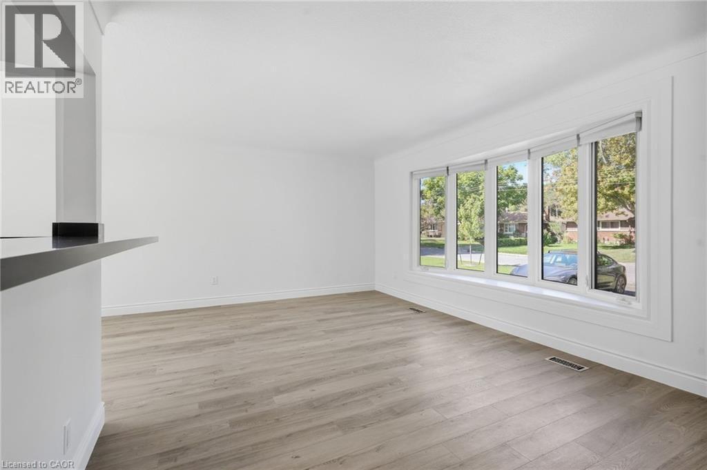 Wood-finish flooring, white painted walls, multi-pane window with white trim, and a black countertop bar - 49 Beverly Crescent, Welland, ON