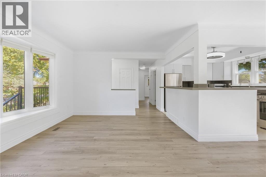 Light wood-finish flooring, white walls, and a large window with white trim - 49 Beverly Crescent, Welland, ON