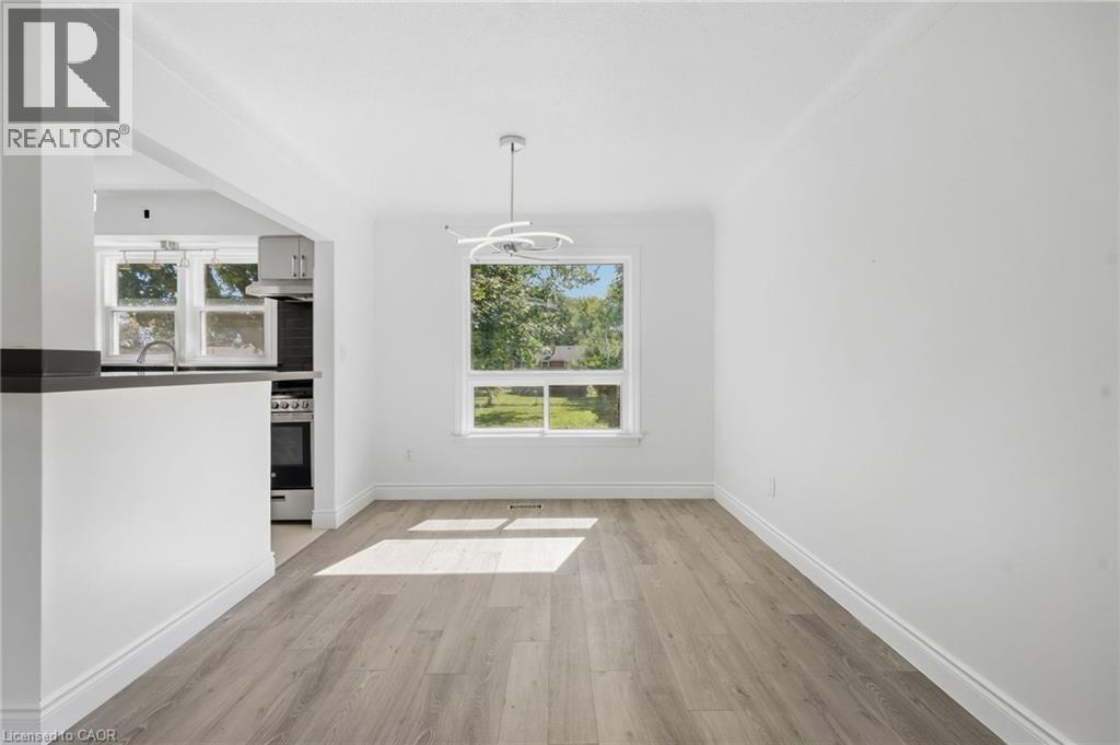 Open concept floorplan featuring a contemporary light fixture, large window, and wood-finish flooring - 49 Beverly Crescent, Welland, ON