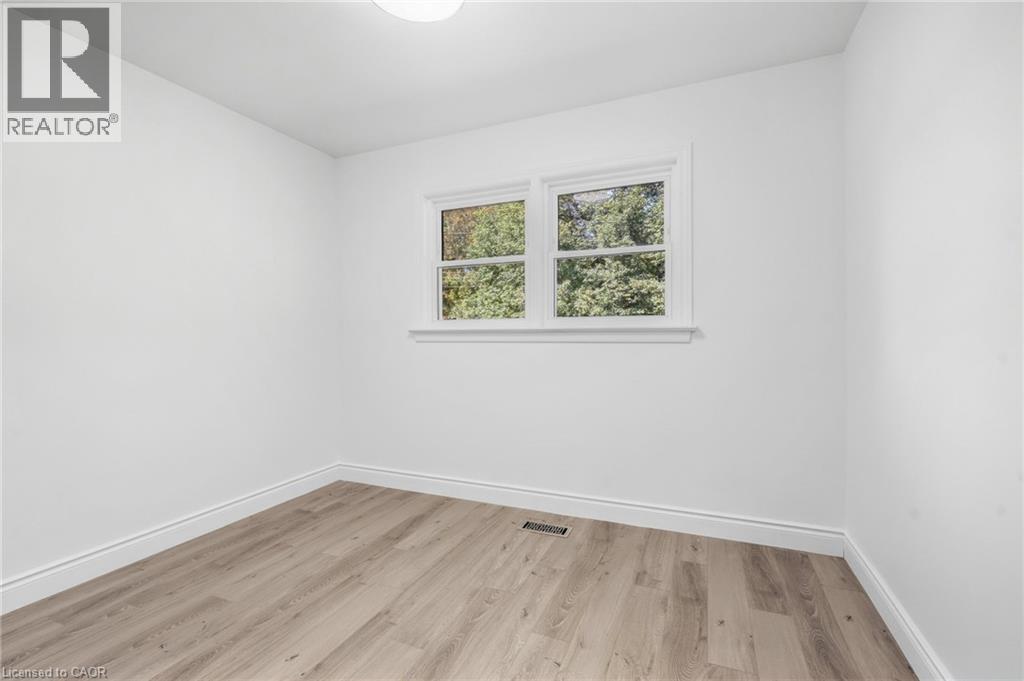 Recessed lighting, wood-finish flooring, white walls, and a window with white trim - 49 Beverly Crescent, Welland, ON