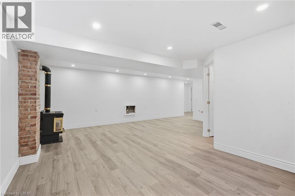 Wood-finish flooring, recessed lighting, brick-clad column, built-in fireplace, and a wood-burning stove - 49 Beverly Crescent, Welland, ON