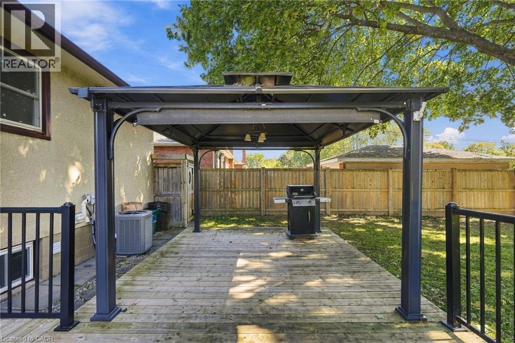 Expansive wood-finish deck with a built-in gazebo featuring a metal frame and covered roof - 49 Beverly Crescent, Welland, ON