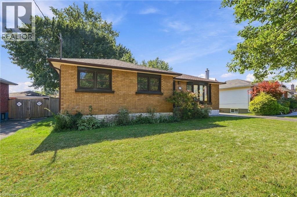 Brick exterior residence with a pitched roof, front lawn, and mature trees - 49 Beverly Crescent, Welland, ON