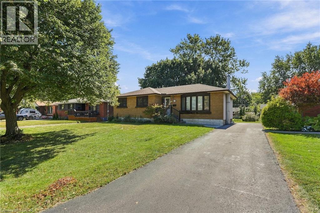 Brick exterior, paved driveway, gabled roof, and mature landscaping - 49 Beverly Crescent, Welland, ON